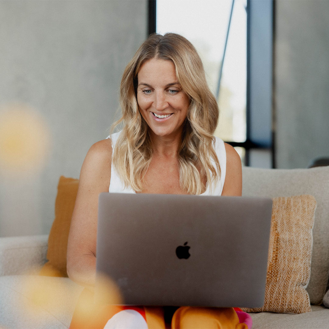 Woman using a laptop on a couch with a blurred background